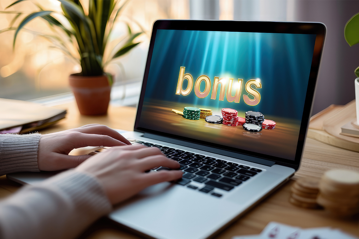 Ekran laptopa z bonusem powitalnym kasyna online, żetony i bębny slotów w tle
